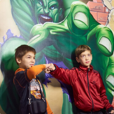 Два ребенка на фоне картины Халка