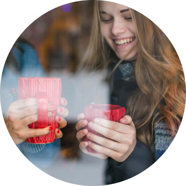 Две девушки, согревающие руки чашкой с горячим напитком