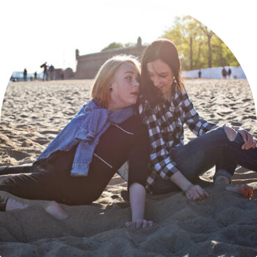 Две девушки на песке спиной друг к другу